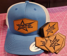 Load image into Gallery viewer, Blue cap with leather patch logo and matching stickers on a pink cutting mat