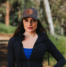 Load image into Gallery viewer, Woman wearing a cap with a logo outdoors
