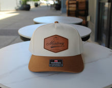 Load image into Gallery viewer, Brown and white cap with leather patch on a table outdoors
